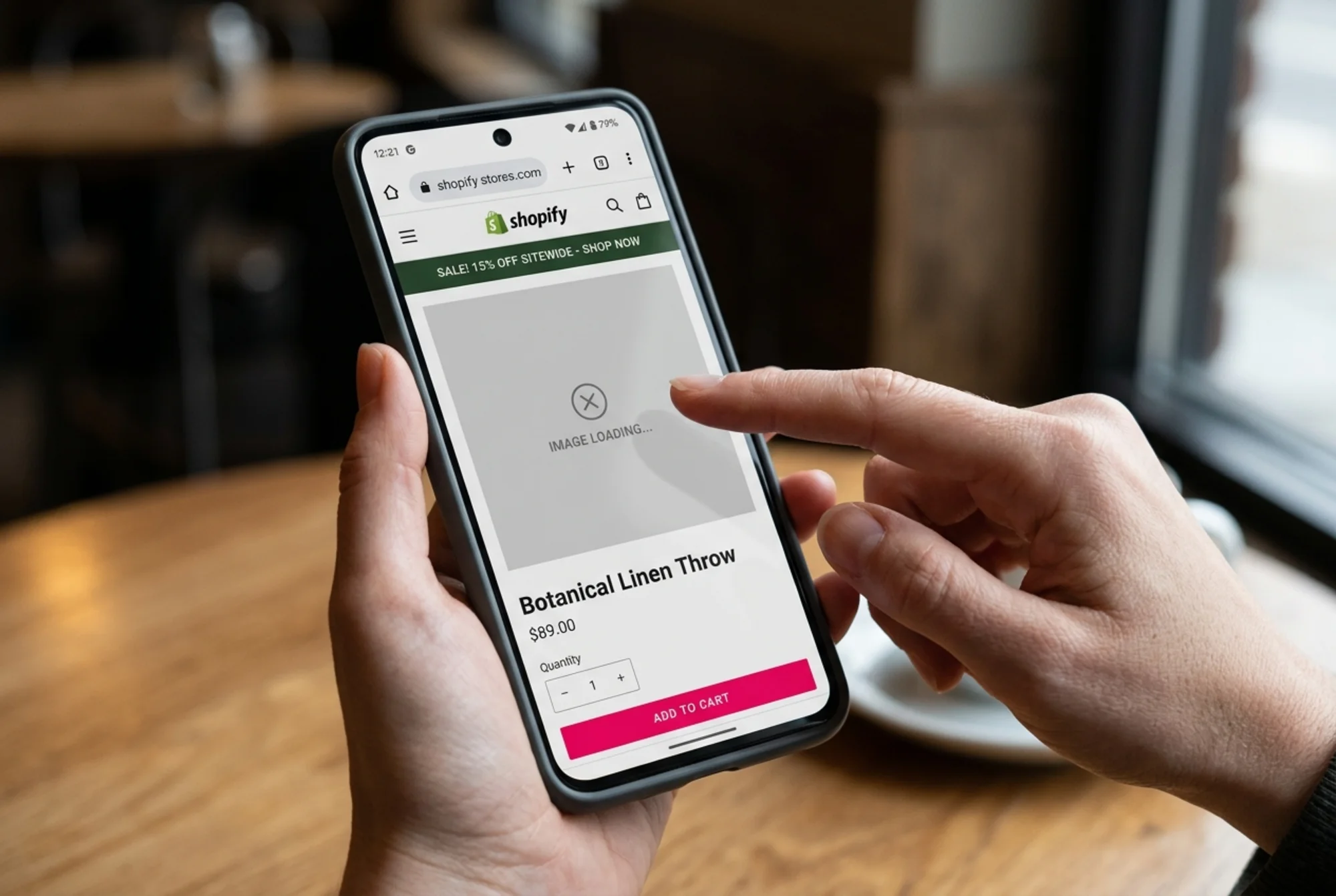 Mobile phone in hand showing a Shopify product page mid-load: hero image still a grey placeholder, an announcement bar dropping in and shoving the price and "Add to cart" button downward, finger hovering mid-tap