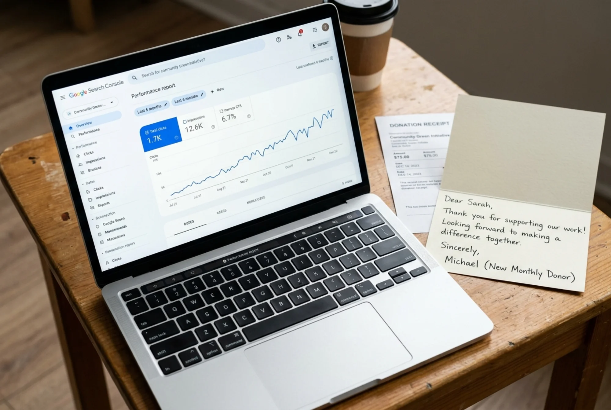 Google Search Console performance graph on a laptop screen showing a rising click trend over six months next to a printed donation receipt and a thank-you card from a new monthly donor